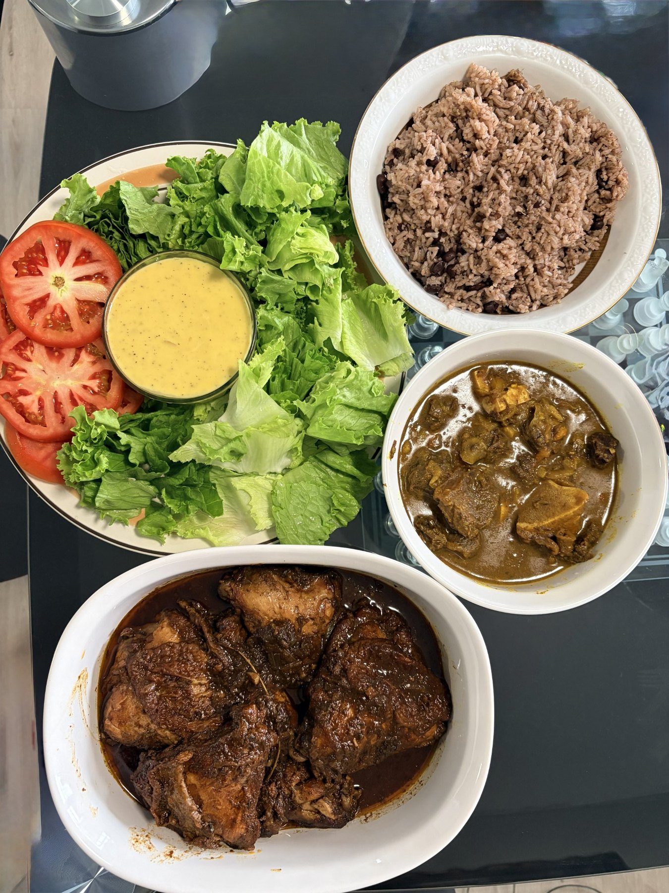 Jamaican meal spread with rice and peas, chicken, curry, salad, and tomatoes
